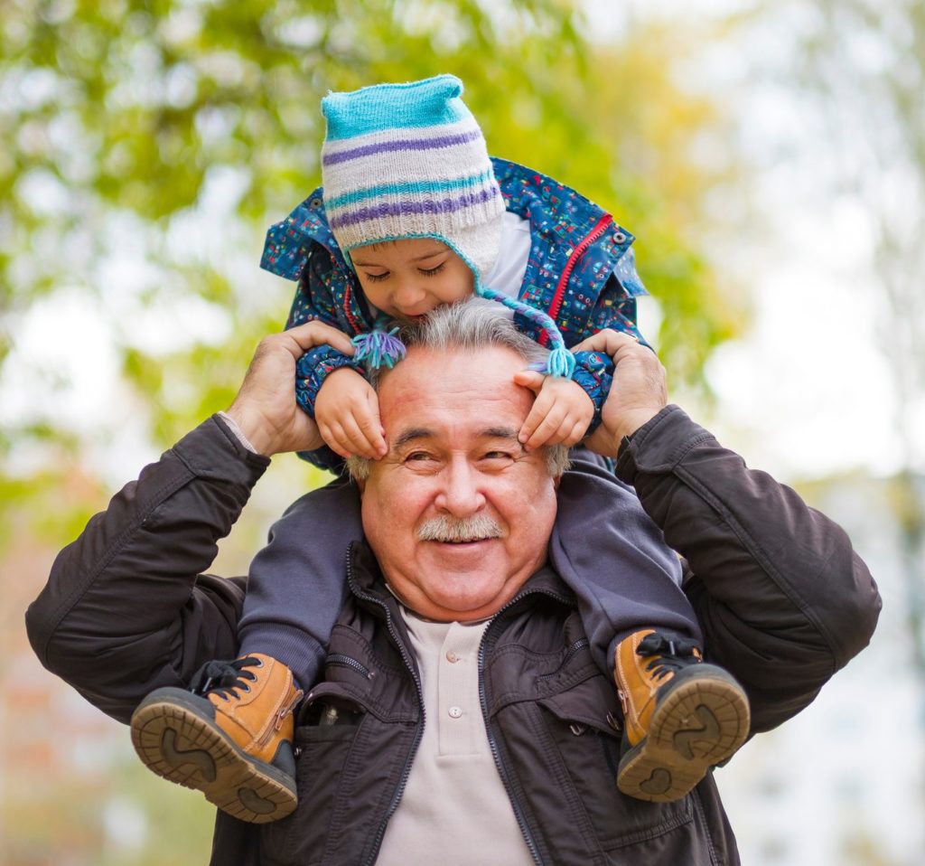 Little boy sitting on the shoulders of his grandpa